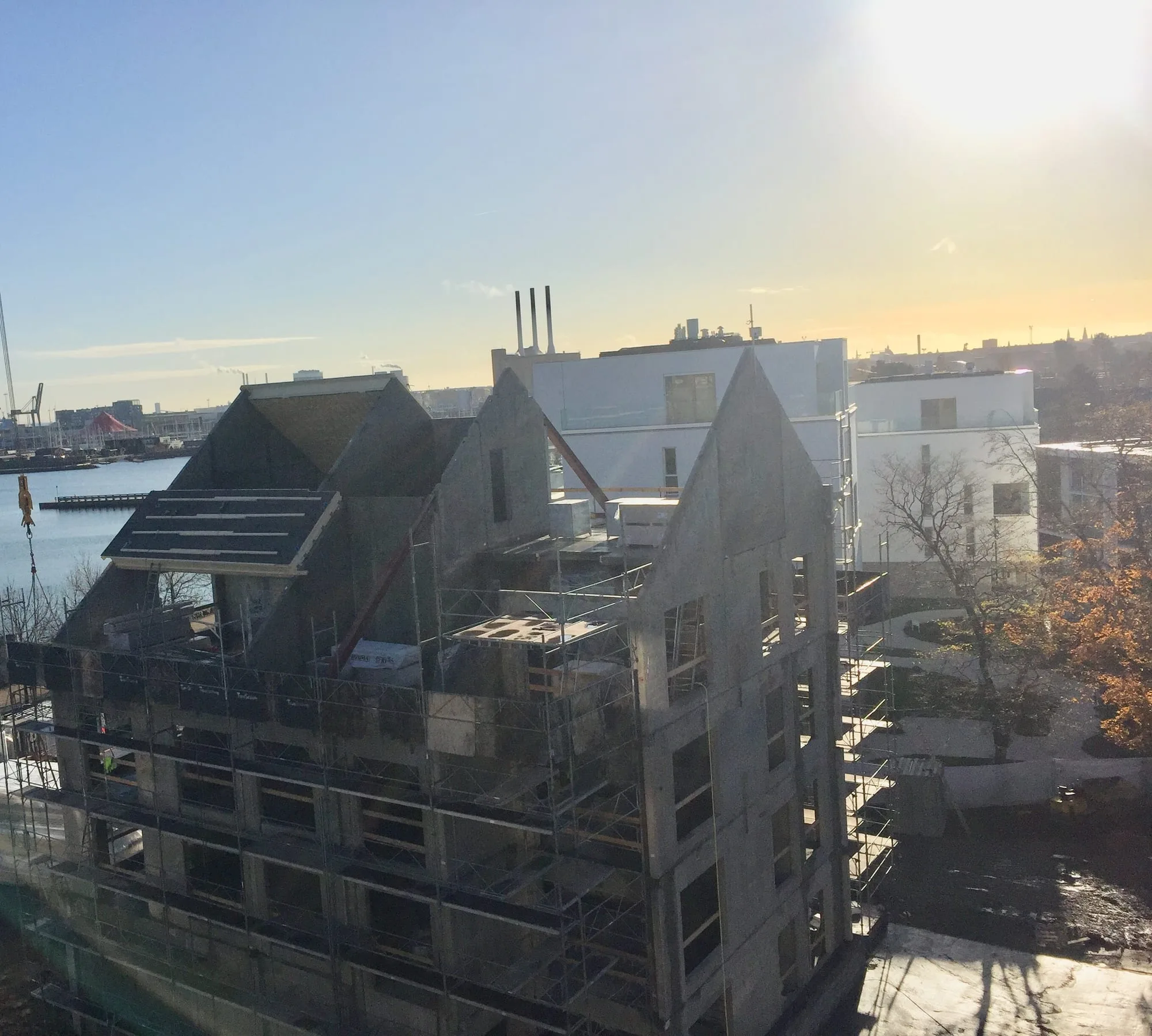 Boligblok i beton under opførelse med stillads og spidse gavle ved vandet, Scherfigs Have, København Ø