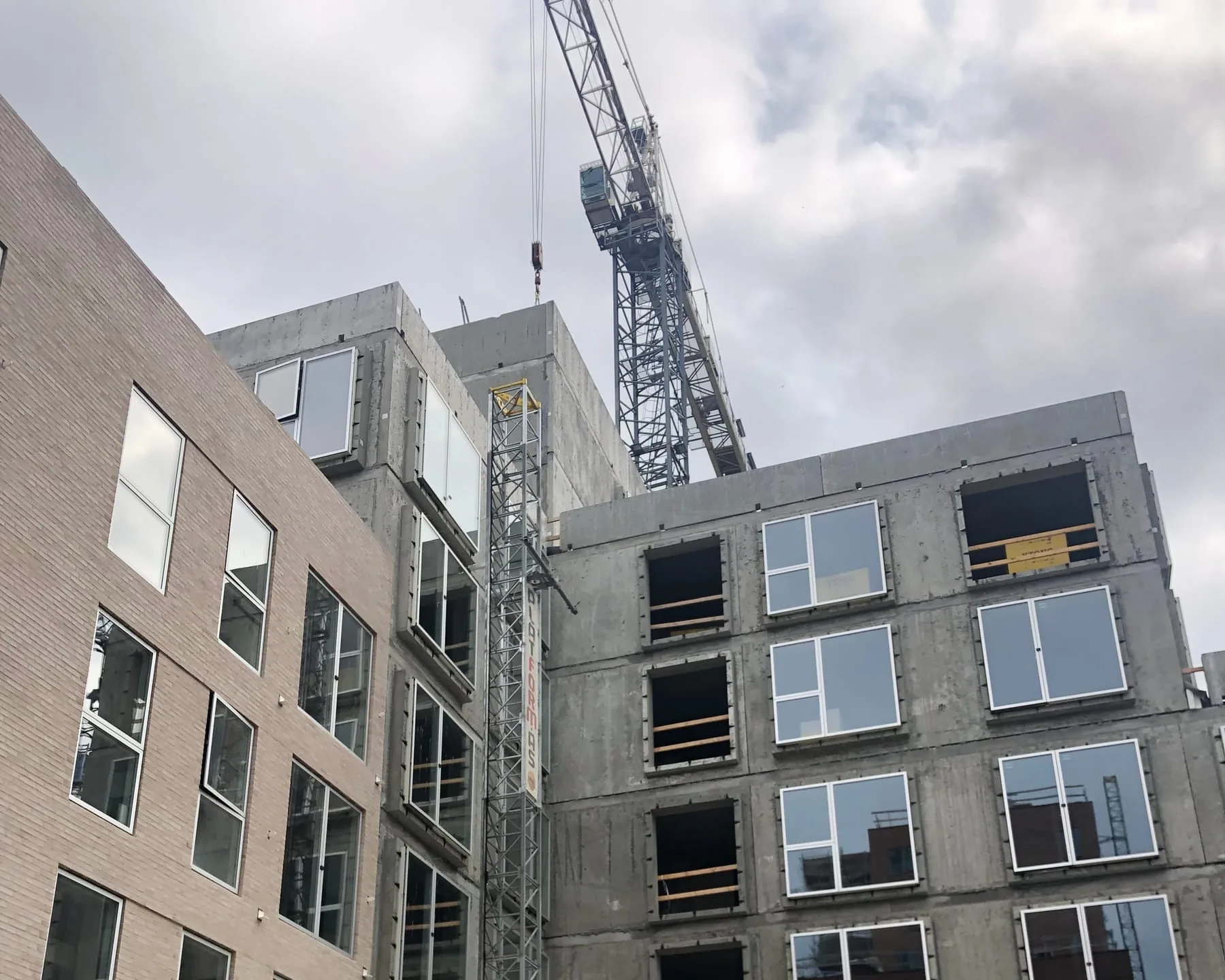 Etagebyggeri i beton og lyse mursten under opførelse med en byggekran over taget, Strandlodsvej 13, København S