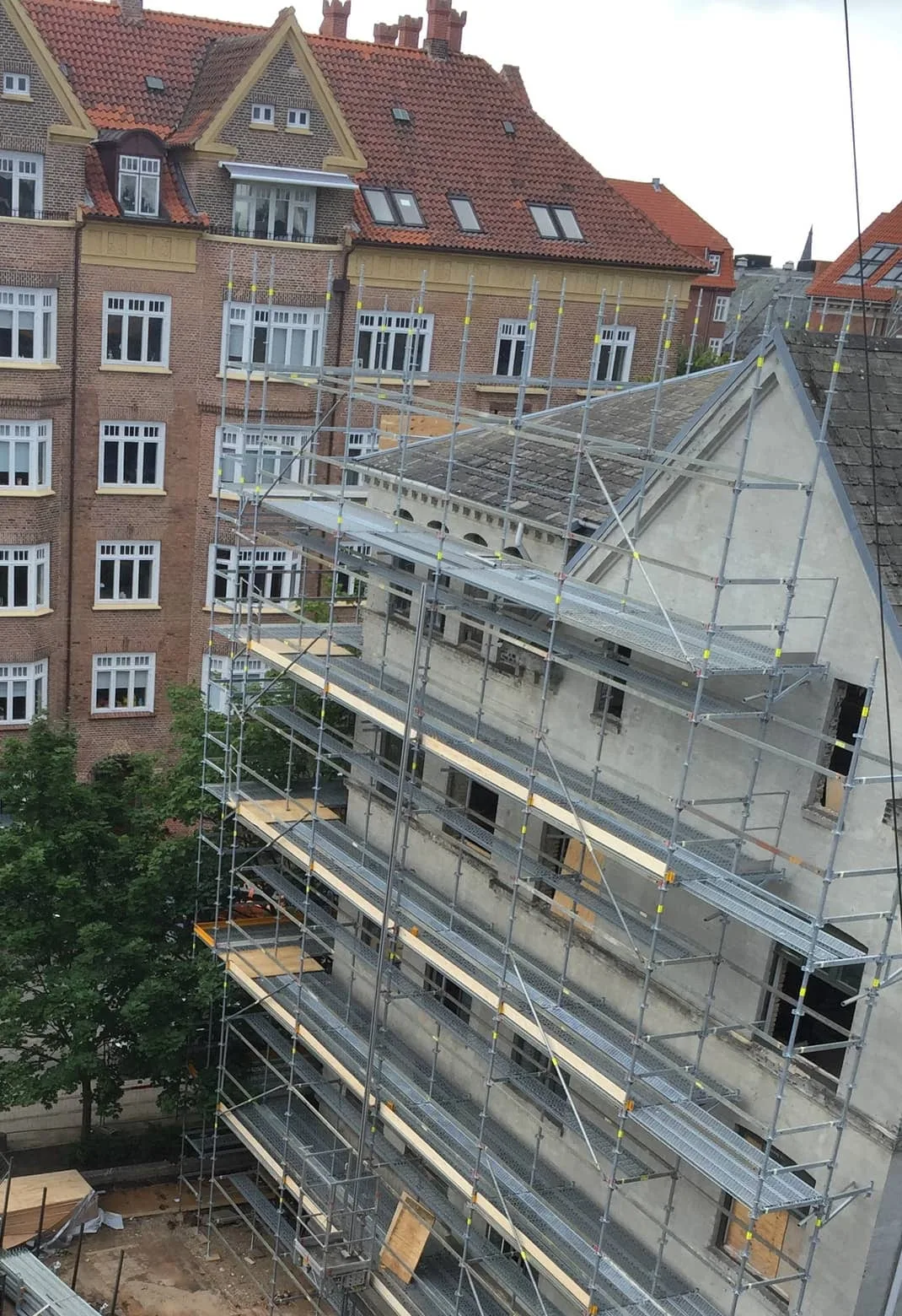 Ejendommen under ombygning med stillads på facaden, set fra gården, og en ejendom i røde mursten bagved, Danasvej 30, Frederiksberg