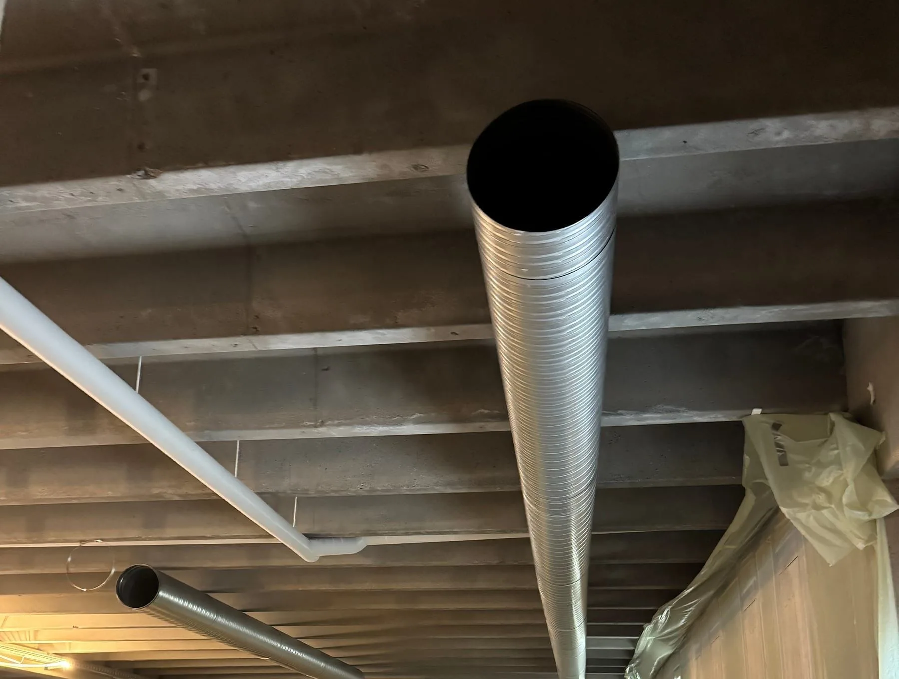To spirokanaler og et hvidt rør under et råt betonloft med bjælker, AB Clausen HQ, Glostrup