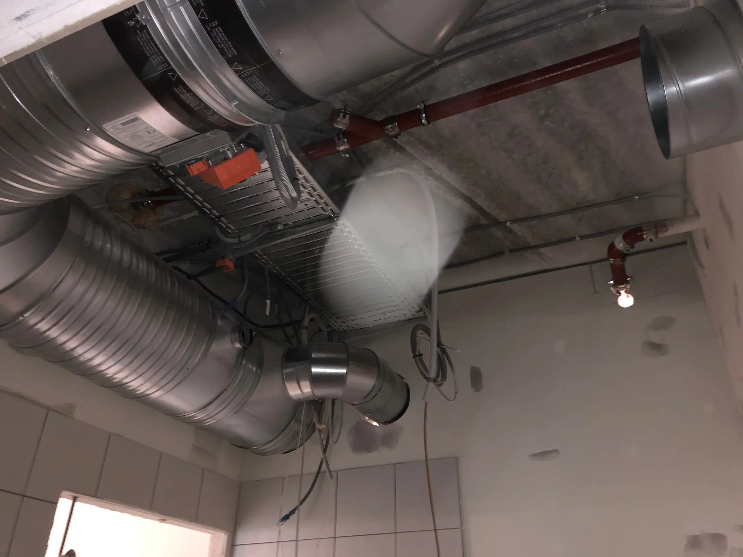 Kanaler med spjæld og orange spjældmotor under loftet, set nedefra, Danasvej 30, Frederiksberg
