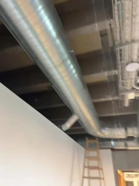 Lang spirokanal under loftet over en hvid væg og en stige, AB Clausen Extension, Glostrup