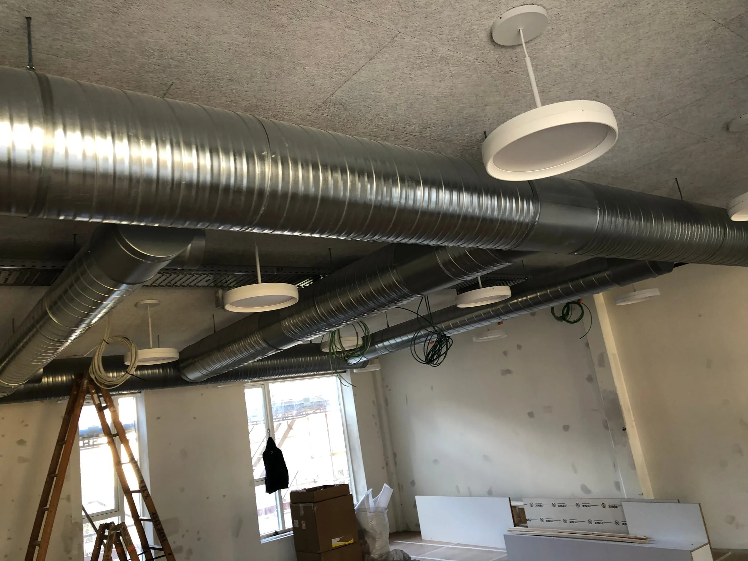 Spirokanaler og runde loftslamper hængt op under loftet i et rum under indretning, Danasvej 30, Frederiksberg